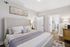 Modern bedroom featuring a cozy upholstered bed with elegant pillows, stylish decor, and natural light enhancing the serene atmosphere.