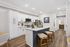 Modern kitchen with elegant white cabinetry, marble countertops, and a sleek island featuring comfortable stools.