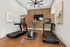 Modern fitness room with two treadmills, an elliptical, and elegant decor, featuring stylish wall art and a large TV for entertainment.