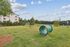 Expansive outdoor area featuring vibrant green grass, playful structures, and a scenic backdrop, ideal for leisure and outdoor activities.