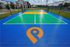 Vibrant outdoor sports court with colorful markings, set against modern apartment buildings and lush greenery.