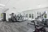 Bright, modern fitness center equipped with treadmills, exercise machines, and large windows overlooking a swimming pool area.