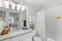 Bright and modern bathroom featuring a sleek granite countertop, elegant lighting fixtures, and a stylish tiled shower with a curtain.