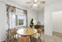 Bright dining room with a round wooden table, stylish chairs, floral curtains, and a modern ceiling fan.