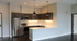 Modern kitchen with sleek stainless steel appliances, elegant pendant lighting, and spacious quartz countertops.