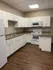 Modern kitchen with sleek white cabinets, wood flooring, and energy-efficient appliances.
