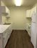 Bright kitchen with white cabinetry, modern appliances, and elegant wood flooring.