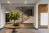 Chic apartment lobby featuring modern staircase, elegant round table with lush green plant, and stylish mailboxes.