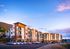 Modern apartment complex under a vibrant sunset sky, featuring balconies and ample parking, offering scenic mountain views.