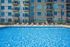 Luxurious apartment complex with a stunning outdoor pool, surrounded by modern balconies and relaxing sun loungers.