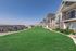 Charming row of modern apartment homes overlooking a lush green lawn, set against a backdrop of rolling hills under a clear blue sky.