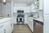 Modern kitchen featuring sleek white cabinets, stainless steel appliances, and elegant hardwood floors.