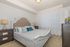 Elegant bedroom with a luxurious tufted headboard, stylish side tables with matching lamps, and sunlit through sheer curtains &ndash; perfect for serene living.
