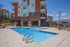Luxurious apartment exterior featuring a pristine swimming pool, modern architecture, and inviting outdoor lounge area.