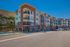 Contemporary multi-story apartment building with balconies and modern architecture, set against a scenic hillside, offering vibrant community living.