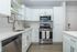 Modern kitchen featuring sleek white cabinets, stainless steel appliances, and elegant hardwood floors.