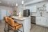 Modern kitchen with sleek white cabinetry, stainless steel appliances, and elegant island seating.