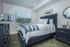 Elegant bedroom with modern decor, featuring a comfy bed with plush pillows, ornate wall art, and sleek white furniture.