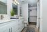 Spacious and modern bathroom featuring a sleek double vanity, bright lighting, and an open layout with convenient access to a large walk-in closet.