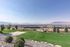 Breathtaking valley view with lush green lawn and sports area overlooking cityscape and distant mountains.