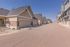 Charming suburban street lined with modern townhomes featuring elegant stone accents and spacious garages, under a clear blue sky.