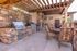 Charming outdoor patio featuring a rustic stone barbecue area with two grills and elegant seating, ideal for entertaining and relaxation.