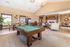 Elegant community room with a pool table, chic seating area, and a cozy dining space, bathed in natural light and featuring modern decor.