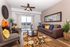 Inviting living room with stylish decor featuring vibrant cushions, elegant armchairs, and a decorative rug under a glass coffee table, enhanced by natural light through large sliding doors.