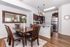 Modern dining area with elegant wooden table and chairs, adjacent to a sleek, fully-equipped kitchen featuring stainless steel appliances and contemporary lighting.