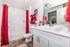 Elegant bathroom with red accents, featuring a pristine white vanity, modern sink, and tub, creating a cozy and inviting atmosphere.