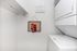 Charming laundry room with modern stacked washer and dryer, featuring a playful sock art display and open shelving.