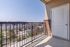 Inviting apartment balcony with stunning views of a modern community swimming pool and surrounding townhouses under a clear blue sky.