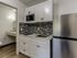 Modern kitchenette with sleek stainless steel appliances, stylish mosaic backsplash, and elegant white cabinetry.