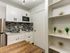 Modern kitchen with sleek white cabinetry, stylish backsplash, and built-in microwave, alongside elegant shelving decor.