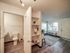 Inviting apartment interior with a cozy living area featuring large windows, elegant flooring, and a convenient bathroom adjacent to a stylish open shelving unit.