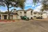 Charming apartment complex exterior with modern architecture, lush greenery, and ample parking space.