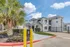 Exterior view of Fusion at Rye Apartments showing gated entry, palm tree, and modern white two-story buildings in Houston TX.