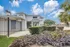Leasing office exterior at Fusion at Rye Apartments with landscaped walkway, modern gray building, and blue sky in Houston TX.