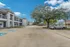 Parking area with cars, trees, and modern two-story apartment buildings at Fusion at Rye Apartments in Houston TX.