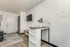 Bright apartment interior at Fusion at Rye with mounted TV, white entry door, wood flooring, and a small table with shelving in Houston TX.
