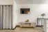 Living area at Fusion at Rye Apartments with mounted TV, small media console, and wood-style flooring in Houston TX.
