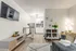 Open-concept living area and kitchen at Fusion at Rye Apartments featuring wood-style floors, mounted TV, modern shelving, and white cabinetry in Houston TX.