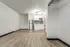 Unfurnished studio apartment at Fusion at Rye in Houston Texas showing an open layout with wood style flooring, a compact kitchen with white cabinets, stainless steel refrigerator, microwave, tile backsplash, and a doorway leading to the bathroom. A closet with a wire shelf and hanging rod is visible on the right side.