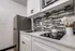 Compact kitchen with white cabinetry, countertop cooktop, and tile backsplash.