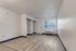 Empty studio room with wood-style flooring, large window, and open closets.