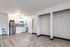 Open studio layout with built-in closets, wood-style flooring, and a view toward the kitchen and bathroom.