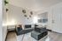 Bright studio living area with large window, wood-style flooring, and flexible open space.