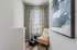 Chic and cozy reading nook featuring a stylish chair, modern abstract artwork, and elegant patterned curtains.