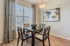 Chic dining area with elegant patterned curtains, stylish artwork, and a modern wooden table set for an inviting ambiance.