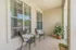 Inviting apartment balcony with cozy seating, potted plants, and large windows offering a serene view.
